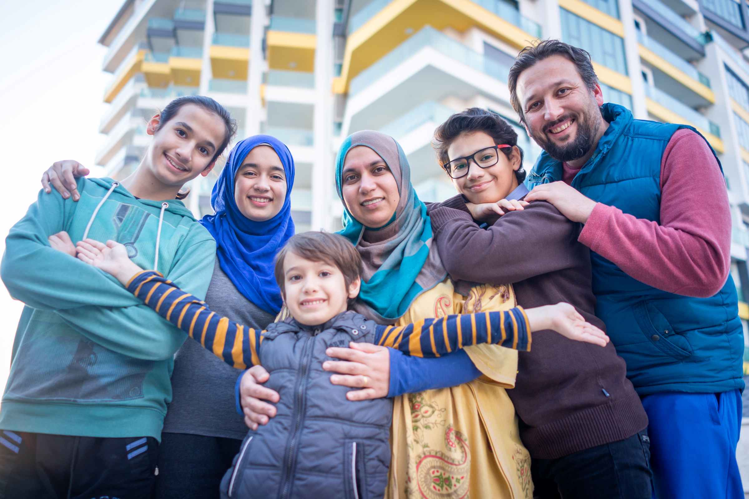 A family of five posing together outdoors at an Eid al-Adha gathering